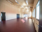 Grâce au bois clair et aux grandes fenêtres : atmosphère conviviale dans le couloir du gymnase